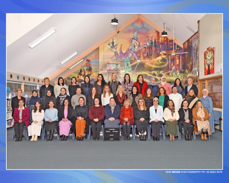 This shows the school staff standing in 3 rows with executive staff sitting in the front row.