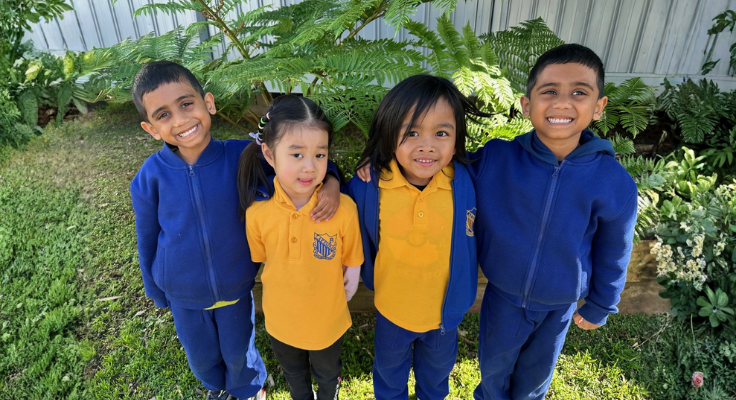 This shows three boys and one girl standing next to each with their hands around each other's backs.
