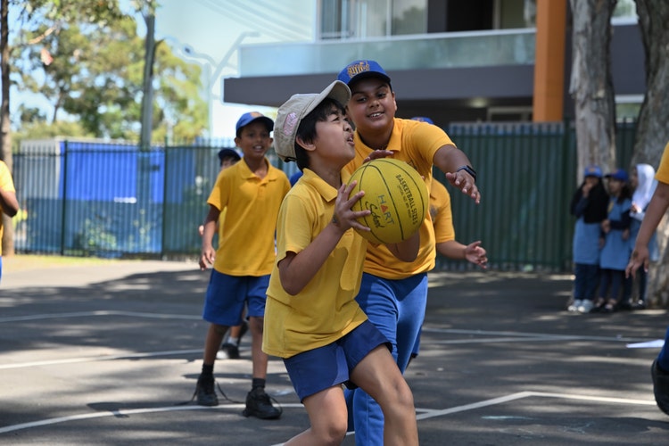 Three boys play basketball with one boy getting ready to shoot the ball.